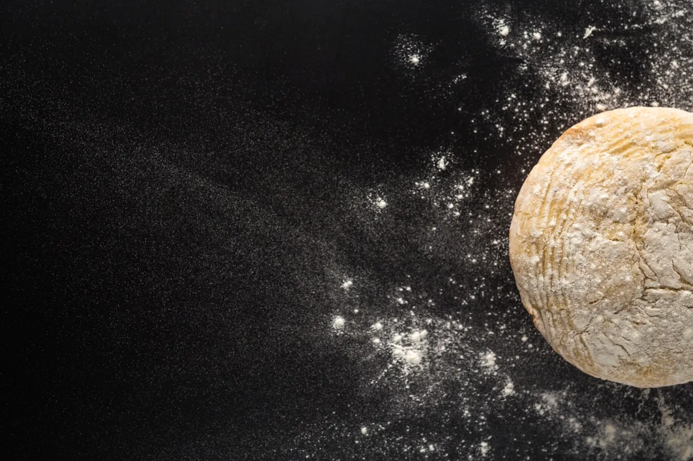 Dough and flour on a dark surface